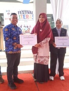 PENGHARGAAN - Ketua Read Aloud Pasbar, Fera Susanti, S.Pd. menerima penghargaan sebagai insan pegiat literasi yang diberikan Kadis Dinas Perpustakaan dan Kearsipan Kabupaten Pasaman Barat, Muharram S.Sos., M.M. di sela-sela Festival Literasi 2026, beberapa waktu lalu. (Foto: Suria Tresna/InsertRakyat.com)