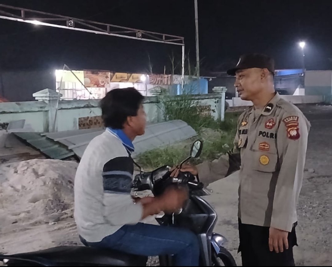 Petugas kepolisian berbincang dengan pria berbaju krem berkerah biru dan bercorak hitam pada lengan di Kecamatan Mandor, Kabupaten Landak.