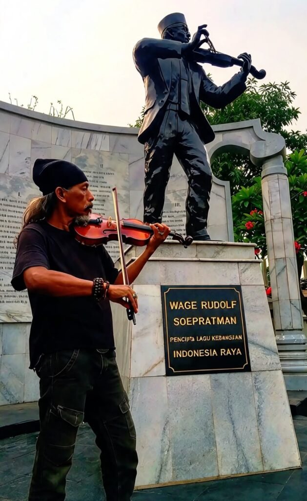 JEJAK SEJARAH: Heri Jolotundo, ilustrator Teater Mantra, berpose di depan patung WR Soepratman di Jalan Kenjeran, Surabaya, menjelang kegiatan Meruwat Indonesia untuk mengenang perjuangan dan merawat ingatan kebangsaan.