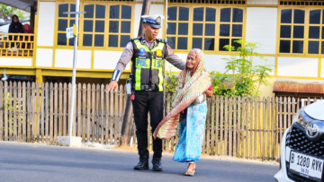 Personel Unit Lantas Polsek Ujung Polres Parepare membantu warga menyeberang jalan saat pelayanan pagi, Senin (19/10/2026).